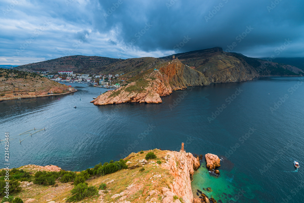 Heavy rain clouds over the bay, rocky mountains and city in the bay, seascape