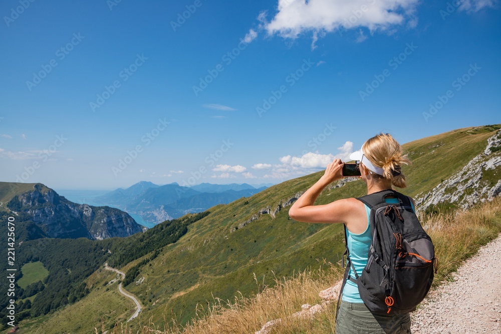Woman taking photo with her phone of Monte Baldo