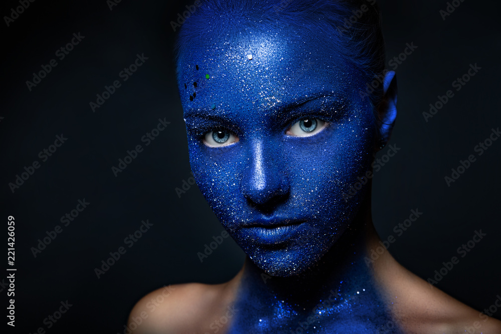 beautiful girl face painted with blue paint with glitter. Stock