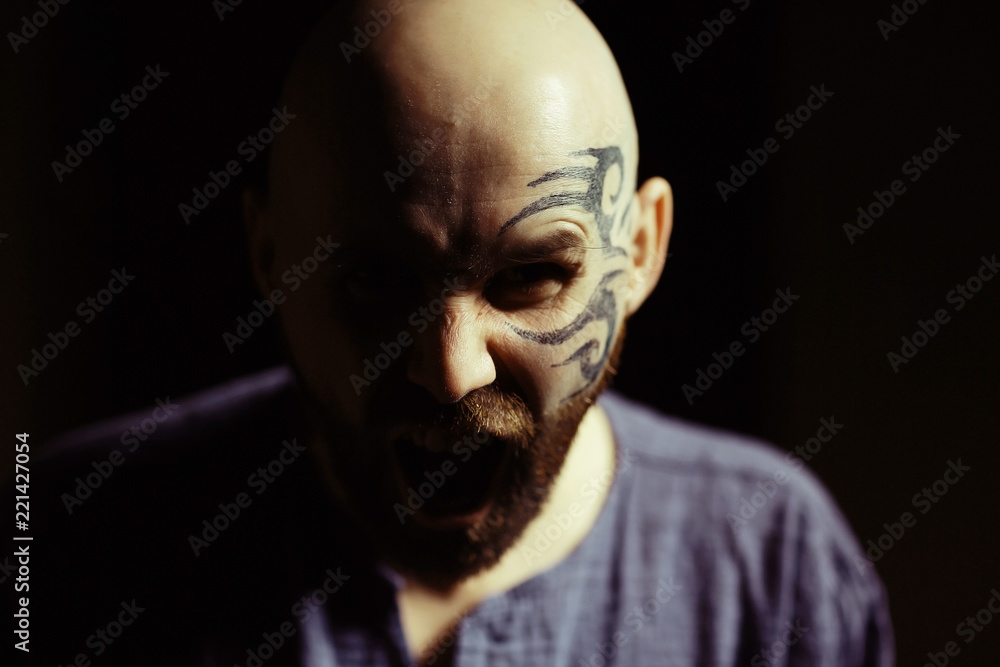 tattoo on the face,  male portrait in the form of an assassin, cosplay,  tattooed brutal man,  guy with a tattooed face
