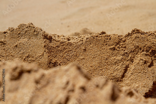 Mountain ranges of sea sand. Reduced model of mountains and rocks from sand. Canyons and cliffs created from sand. The concept of the desert and mountain ranges. Focus in the background.
