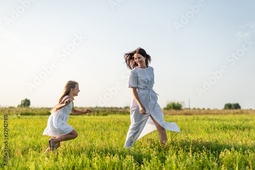 mother and daughter having fun in green meadow together