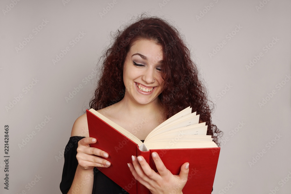 smiling teenage girl enjoys reading a funny hardcover book smiling teenage girl enjoys reading a funny hardcover book