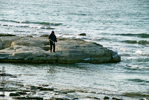Рыбак с удочкой на Каспийских камнях