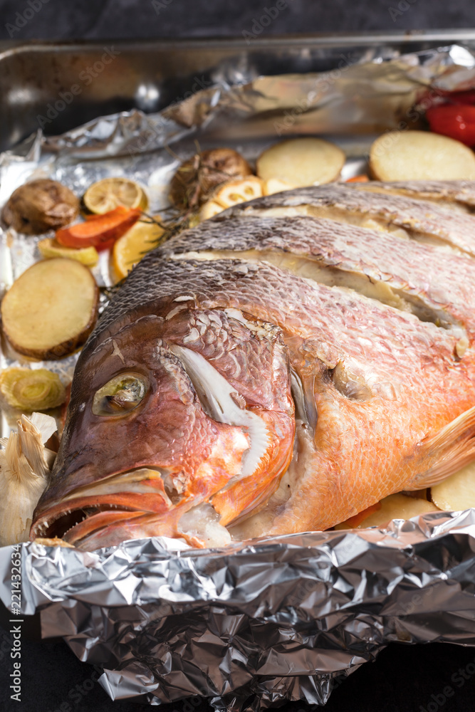 Oven backed red snapper fish with vegetables, just from the oven, vertical composition Oven backed red snapper fish with vegetables, just from the oven, vertical composition