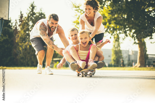 Parents pushing kids on skateboard.