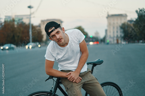 Outdoor portrait of a modern young man in the street, sitting on