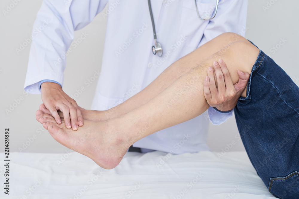 Anonymous medical practitioner helping crop man to do exercise for legs during rehabilitation session in doctor's office Anonymous medical practitioner helping crop man to do exercise for legs during rehabilitation session in doctor's office