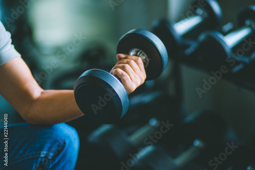 Close up of fit young hand caucasian big muscle in sportswear. Young man holding dumbbell during an exercise class in a gym. Healthy sports lifestyle, Fitness concept.