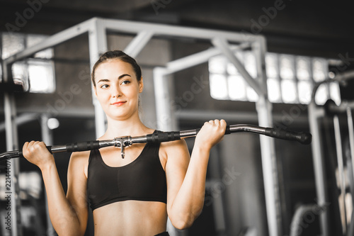 Fit beautiful young woman caucasian posing at the camera in sportswear. Young woman holding dumbbell during an exercise class in a gym. Healthy sports lifestyle, Fitness concept. With copy space.