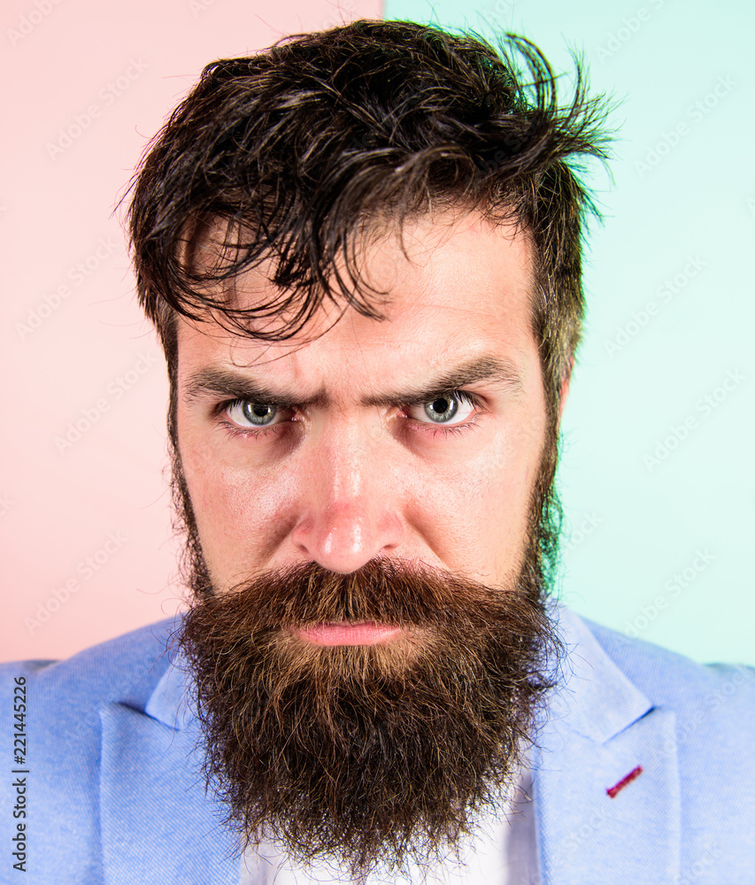 Man bearded hipster on strict face pink blue background. Hipster guy with  messy tousled hair and