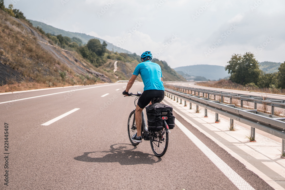 Fototapeta premium Man riding a bike on an empty highway
