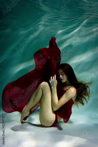 Woman under the water in a red dress.