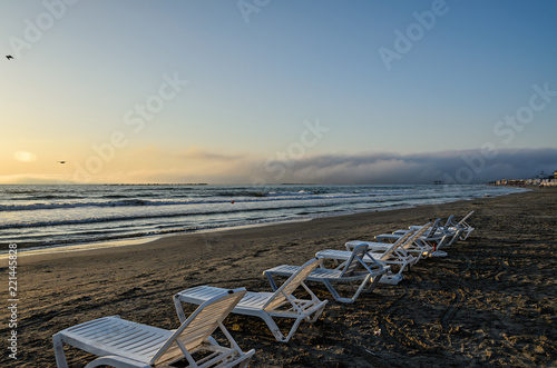 Sunbeds on the beach of Black Sea at sunrise, warm sunshine atmosphere © Negoi Cristian