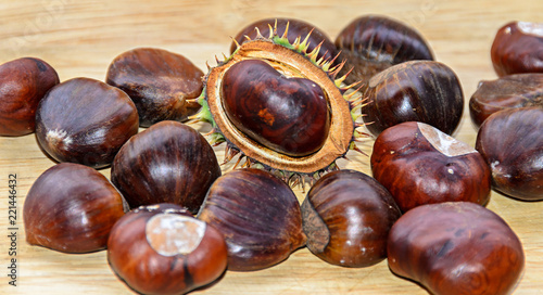 Edible brown chestnuts close up, wooden background