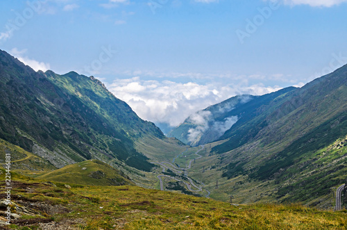 The Transfagarasan road in Fagaras mountains, Carpathians with green grass and rocks, peaks in the clouds