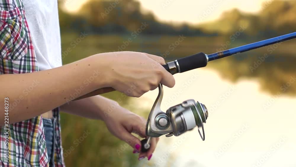 hand with spinning and reel on the summer lake