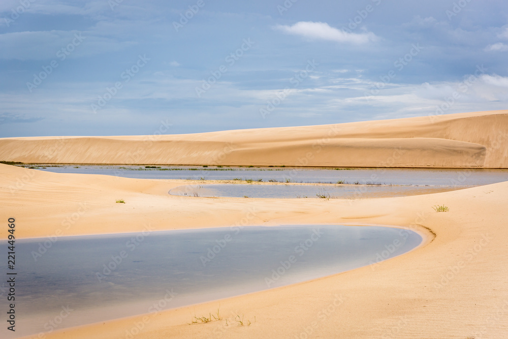 The colorful vast desert landscape of tall, white sand dunes and seasonal rainwater lagoons at the Lençóis Maranhenses National Park, Brasil