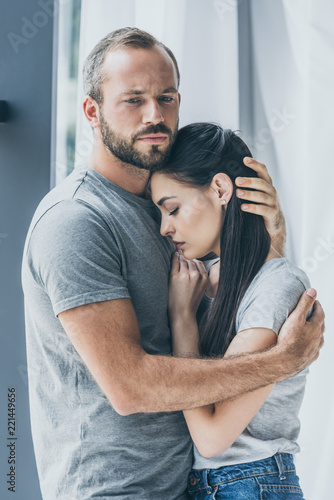 upset bearded man hugging and supporting depressed young woman