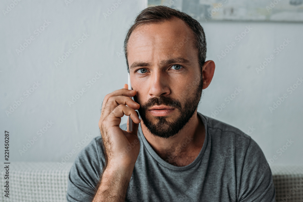 frustrated bearded man talking by smartphone and looking at camera frustrated bearded man talking by smartphone and looking at camera