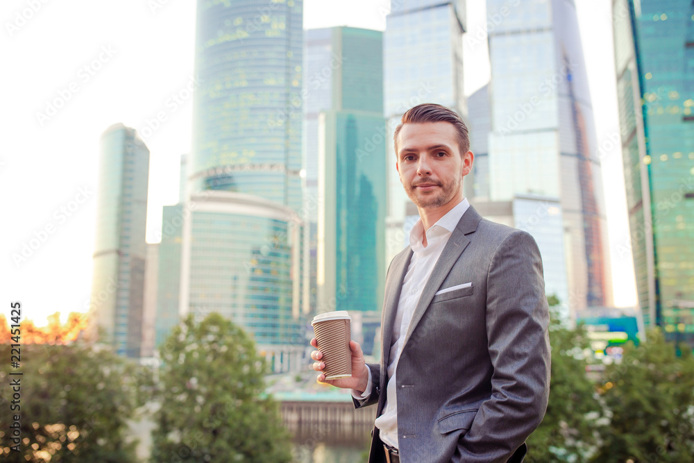 Businessman looking on copy space while standing against glass skyscraper Businessman looking on copy space while standing against glass skyscraper