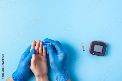 Nurse making a blood test with lancet. Man's hand with red blood drop with Blood glucose test strip and Glucose meter