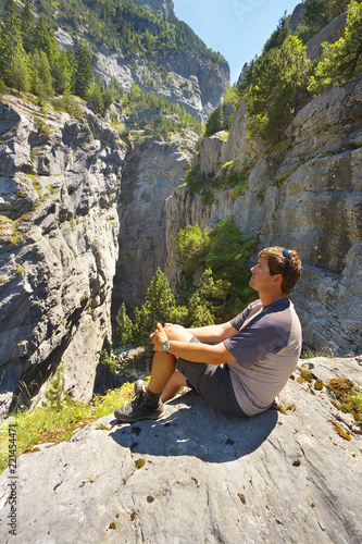 Resting tourist watching a deep limestone gorge Gletscherschlucht nearby resort of Grindelwald, Switzerland photo