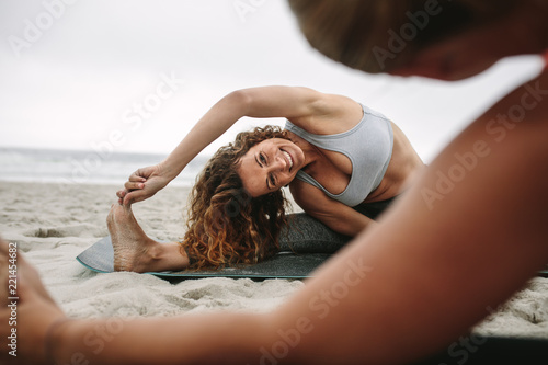 Fototapeta Naklejka Na Ścianę i Meble -  Women practicing yoga positions sitting on the beach