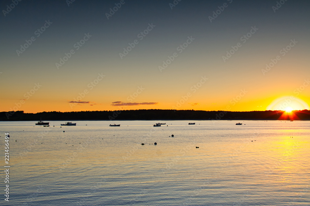 Boats sitting at anchor in Kettle Cove, Main during sunset.