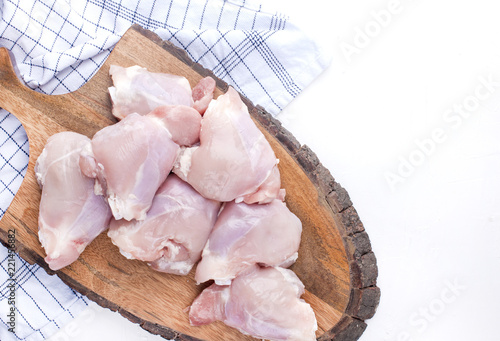 Chicken with oranges raw on a wooden board and white table. Preparation of a delicious meaty dinner. Top view