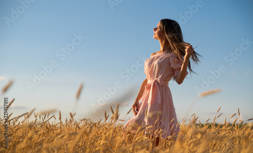 Woman in wheat field at sunset