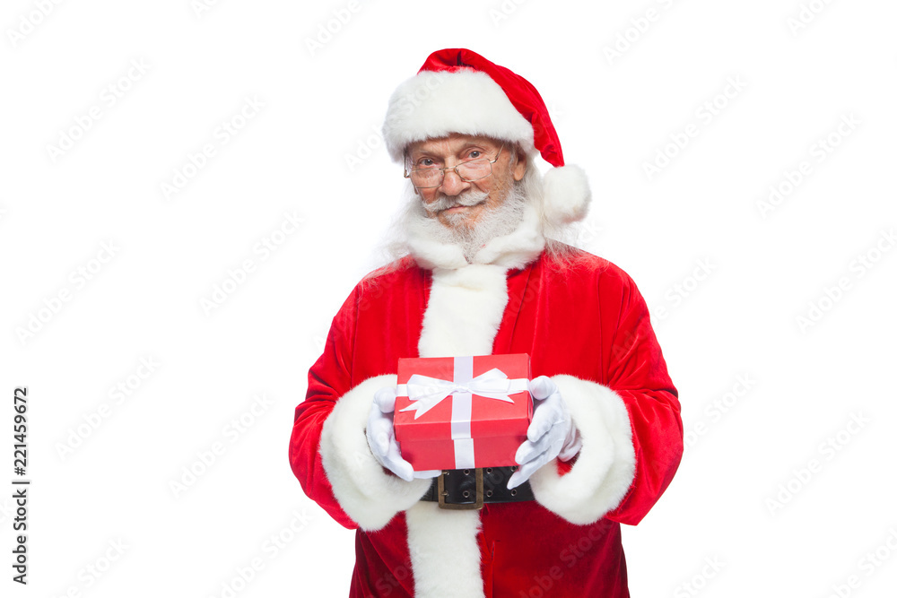 Christmas. Smiling Santa Claus in white gloves is holding a gift red box with a bow. Pointing at the gift. Isolated on white background. Christmas. Smiling Santa Claus in white gloves is holding a gift red box with a bow. Pointing at the gift. Isolated on white background.