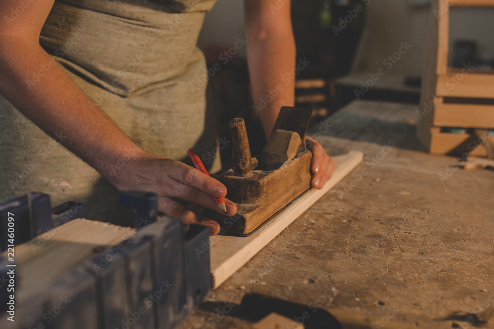 a man an apron polishes the Board in a carpentry workshop a man an apron polishes the Board in a carpentry workshop