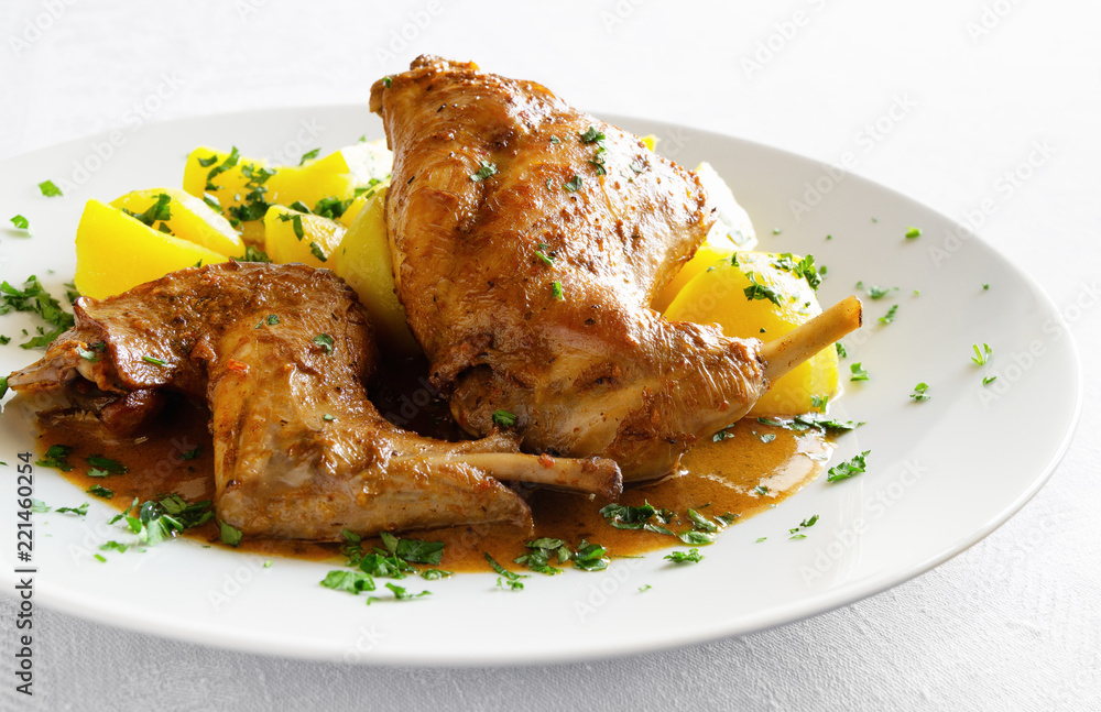 Fotografie stewed in white wine with spices rabbit legs with gravy and potato sprinkled wit
