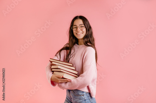 portrait of young student with glasses holding a old book over pink background