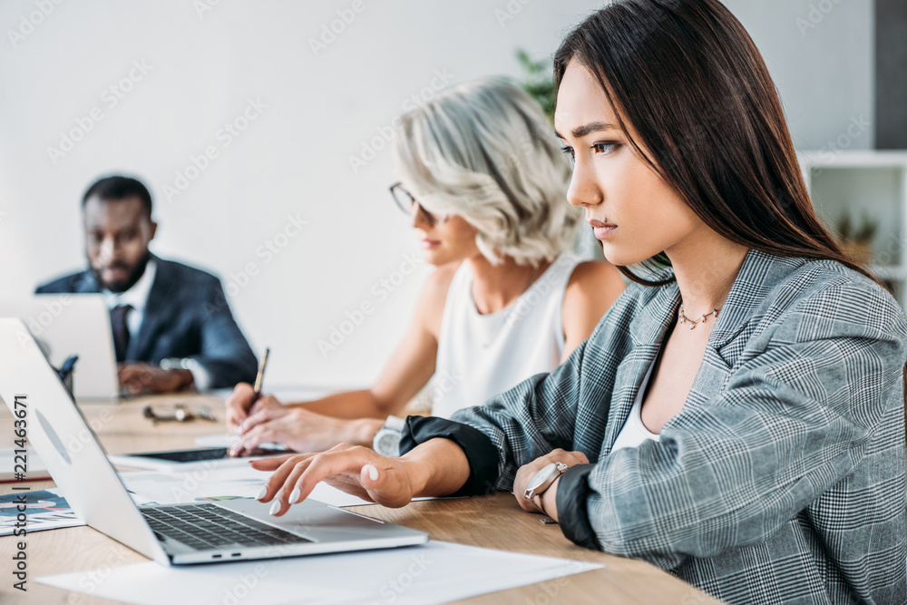 side view of multiethnic businesspeople working at table in office side view of multiethnic businesspeople working at table in office