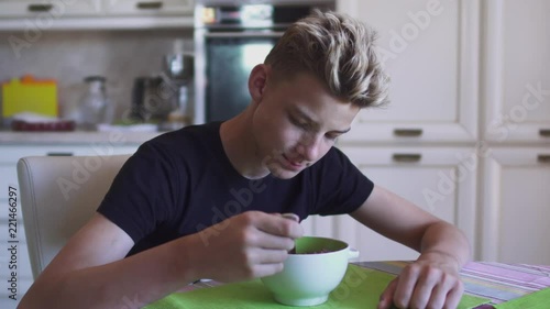 Blond boy eats breakfast at the kitcken photo