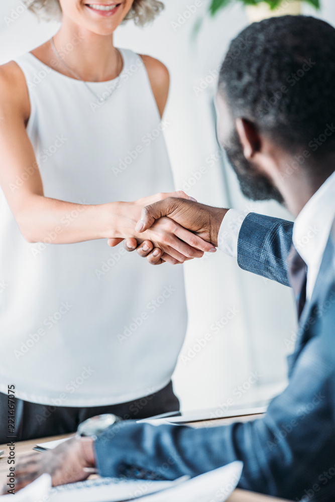 Fototapeta premium cropped image of multicultural businesspeople shaking hands in office