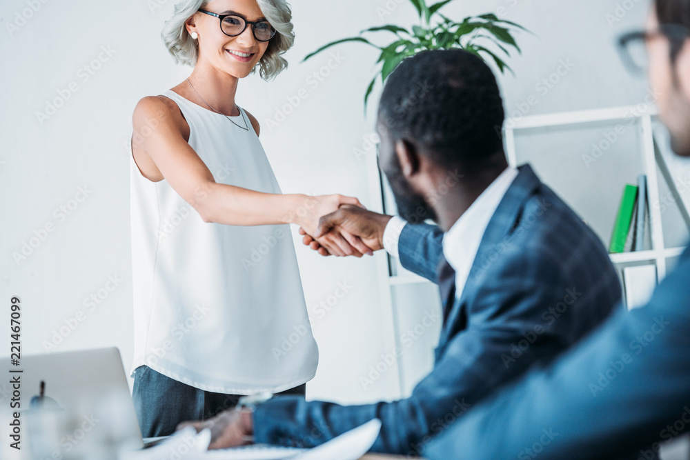 african american businessman and caucasian businesswoman shaking hands in office african american businessman and caucasian businesswoman shaking hands in office