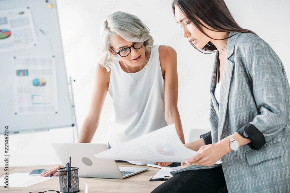 Fototapeta premium multicultural businesswomen looking at documents in office