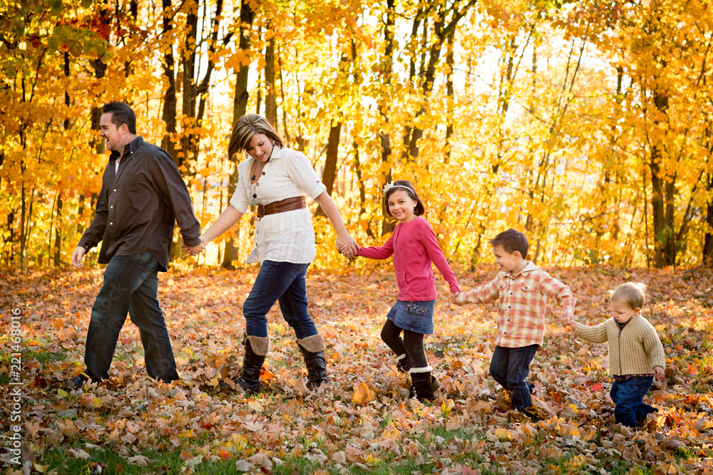 Family Holding Hands and Walking in Autumn Park Family Holding Hands and Walking in Autumn Park