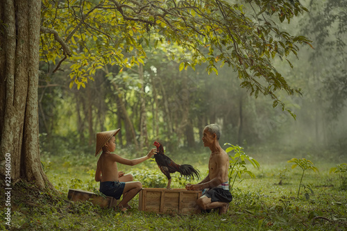 Asian farmer with son are training his fighting cock at countryside. photo