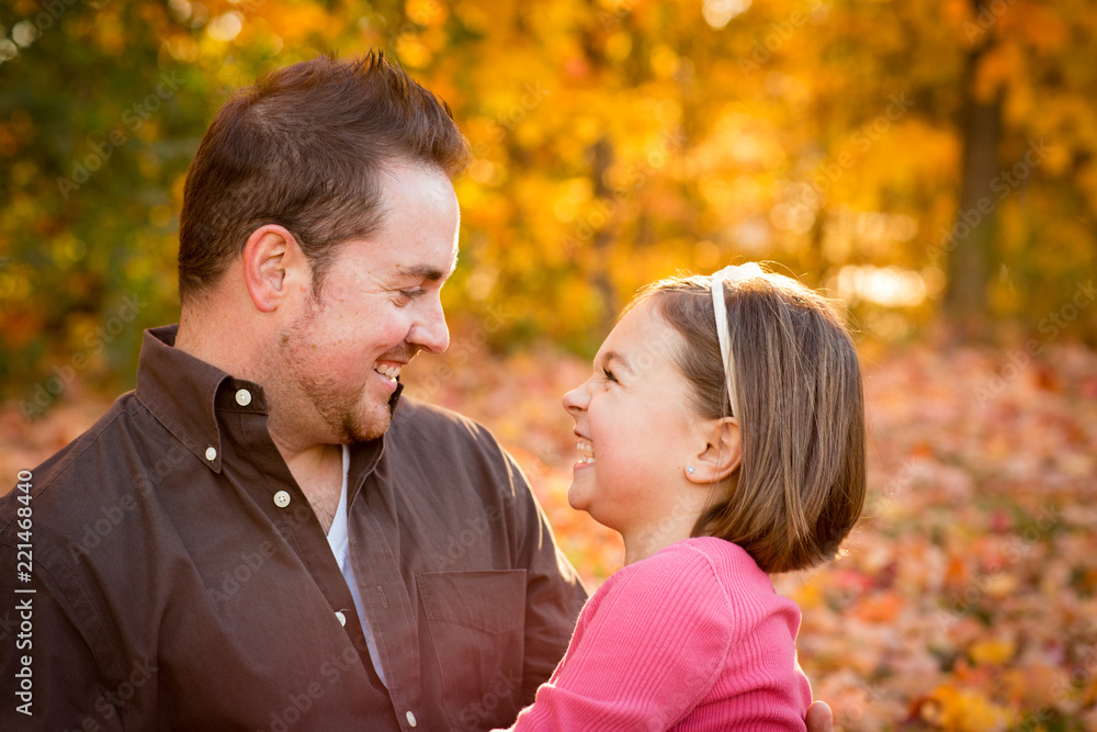 Happy Father and Daughter Sitting in Autumn Park Happy Father and Daughter Sitting in Autumn Park