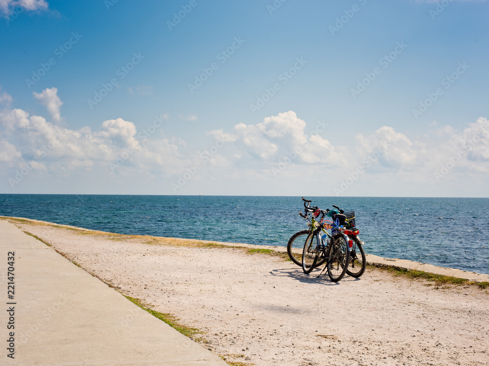 Two bicycles on the background of the sea and sky with clouds.