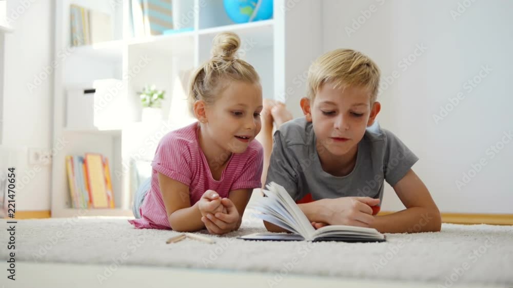 Happy children reading books on the floor at the school library Happy children reading books on the floor at the school library