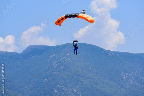 parachutist descends against a blue sky, in the background the mountains © Stefania