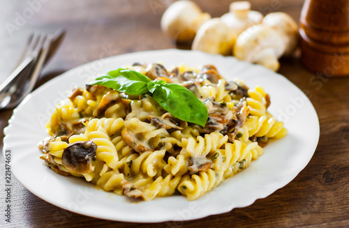 fusilli pasta with mushroom and cream sauce in white plate on a wooden background photo