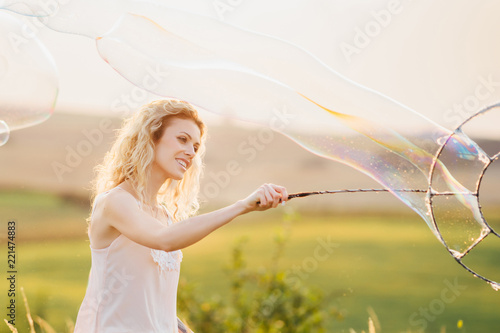 Girl doing soap show at sunset. Original genre. Large soap bubbles
