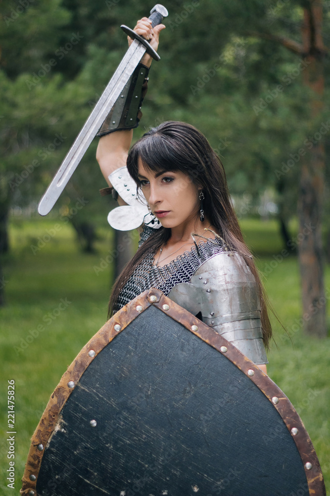 A beautiful warrior girl in a chain mail, a sword and a shield in her hand.