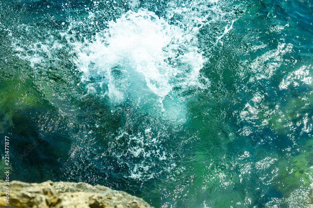 Obraz premium A boy is jumping from the cliff into the sea wiht big water splash on a hot summer day. Holidays on the beach. The concept of active tourism and recreation